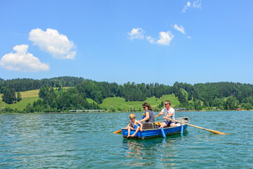 Fototapeta na wymiar Familie hat Spass mit einem Ruderboot auf dem idyllischen Alpsee im Allgäu