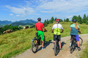 Drei Radfahrer mit E-Bikes genießen die herrliche Natur im östlichen Allgäu
