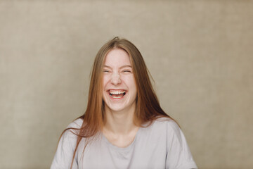 Portrait of young happy laughing caucasian woman at casting movie auditions against beige background
