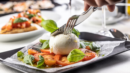 Cutlery used to cut into a ball of Mozzarella di Buffala on a Caprese style salad