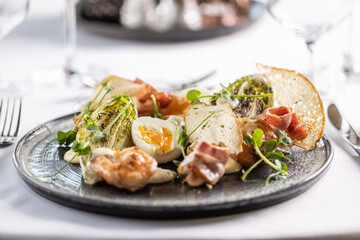 Appetizer in a form of ceasar salad with shrimps, toasts and egg