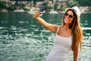 Beautiful woman having a good time at the beach on summer vacation, taking a selfie
