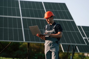 Modern laptop is in hands. Man is doing operating and maintenance in solar power plant © standret