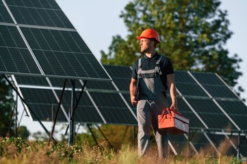 Red repair toolbox is in hands. Man is doing operating and maintenance in solar power plant