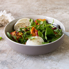 bowl with salad with peaches, arugula and mozzarella on the table