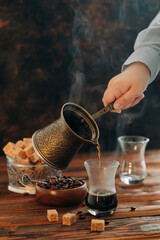 Hand making hot turkish coffee espresso on the dark background