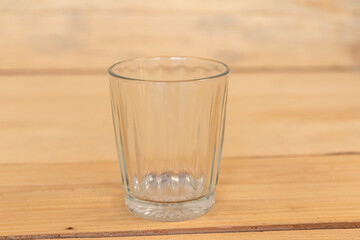 Water glass empty on a wooden table close up.