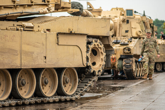 American United States Marine Corps soldier standing under the rain near an Abrams armoured tank, NATO response force