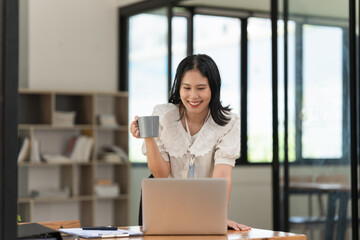 Fototapeta premium Financier a asian woman works, uses a laptop, makes a report to a finance company. Accounting and financial concept