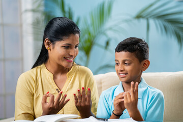 Happy indian mother teaching her son to do maths homework at home - concept of home schooling, tutor and education