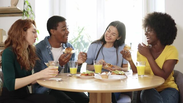 Multiethnic friends chatting while eating breakfast at home