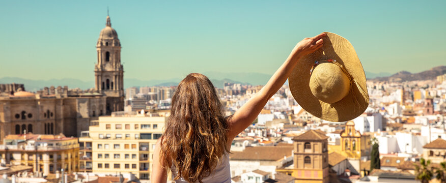 Rear view of woman with hat looking at panoramic skyline of Malaga city- Spain