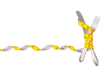diet, slimming: silver knife and fork wrapped with yellow tape measure