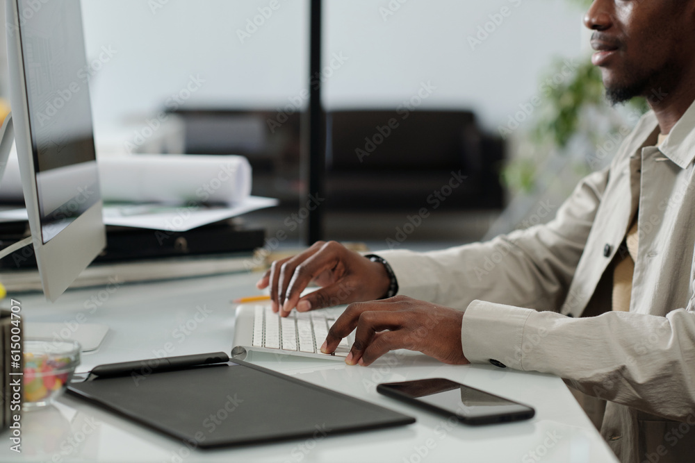 Aufkleber close-up of young african american designer typing on computer keyboard while sitting by desk and wo
