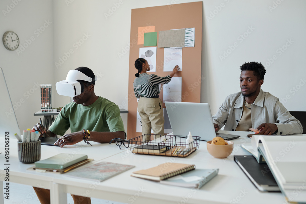 Aufkleber young african american webdesigner looking at laptop screen while sitting by workplace next to colle