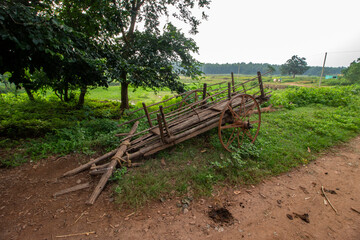 A traditional bullock cart on village road of Bengal. Paddy field on backside side of the road and small plateau hill in background.