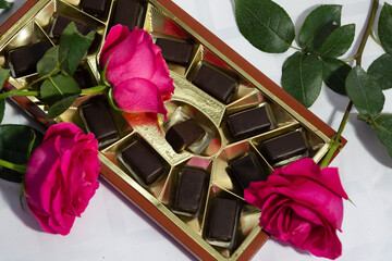 Box of chocolate candies with three pink roses on a white background 21 april 2023. Russia.