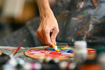 Obraz premium Closeup view of male artist mixing color oil painting on palette. Art, hobby and leisure activity concept