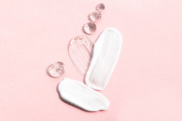 Cosmetic textures on a pink background, top view. Smears of body cream, serum drops of rfgcb hyaluronic acid in the shape of a heart.