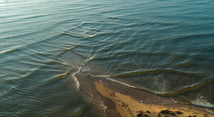 Small waves on the river are lapping against the sandy shore. Wave background on the sand. High...