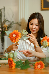 Pleasant Asian woman making a bouquet with fresh flowers at floral shop. Floristry and small business concept