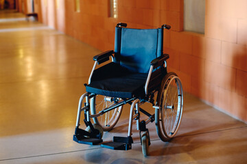 Empty wheelchair of person or patient with disability standing in spacious corridor of hospital or...