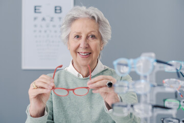Senior woman choosing glasses at the eyewear shop