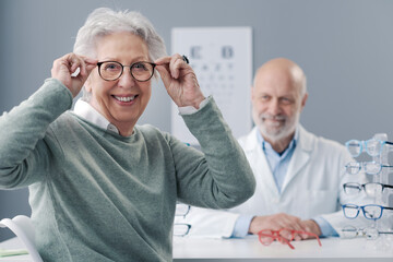 Happy senior lady choosing prescription glasses - obrazy, fototapety, plakaty