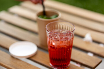 Closeup of glass with drink standing on desk outdoors cafe. Relaxation concept, refreshing drink, alcohol  cocktail, selective focus 