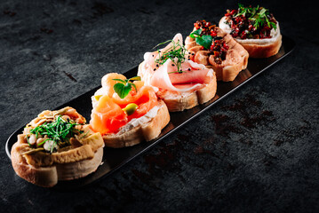 bruschetta set, various bruschettas with toppings on black plate