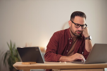Businessman working alone at home office, feeling tired.