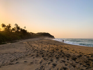 person traveler walking on the sandy beach with the sunset in the caribbean sea