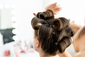 The hairdresser curls the model's hair. Curling iron for curling hair close-up.