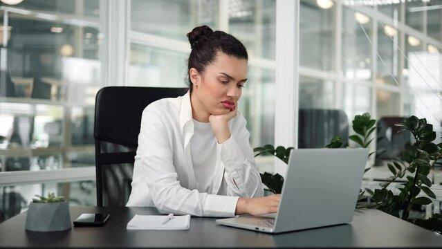 Boring unmotivated hispanic young woman office worker businesswoman tired from working with laptop. Listening online lecture by computer at office. Female latin employee cannot concentrate on work.