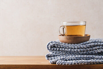 Сup of hot tea and blue knitted plaid on wooden bench. Close-up view of home comfort