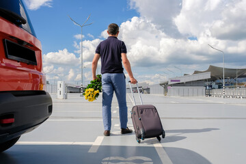 Man with luggage in airport parking. View from the back.