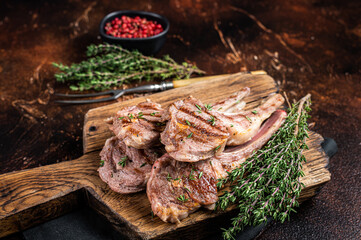 Grilled New Zealand Lamb Chops, mutton cutlets on wooden board. Dark background. Top view