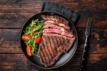 Barbecue grilled and sliced wagyu Rib Eye beef meat steak on a plate. Dark background. Top view