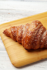 Freshly baked croissant with powdered sugar on wooden board