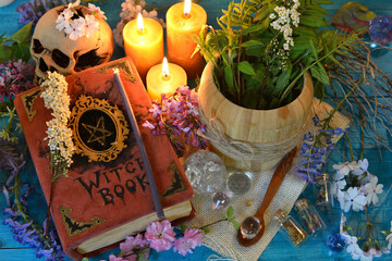 Old witch book with mortar and candles on ritualaltar table. Occult, esoteric and fortune telling still life. Mystic background with vintage objects
