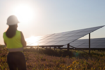 Female engineer looking at solar panels. Invisible figure, blurred. Positive atmosphere. © MAXSHOT_PL