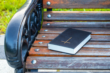 a forgotten bible lies on a bench