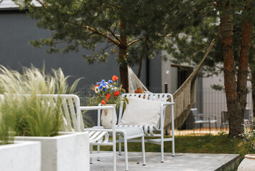 Wild flower bouquet (Cornflowers, chamomiles wheat and poppies) in terracotta vase on summer terrace. Wildflower and grass varieties.