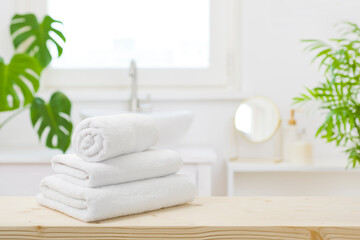Fototapeta na wymiar Spa towels on table with copy space in blurred bathroom