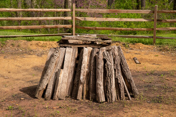 Split logs firewood form a neat circular stack for a bonfire in a rural setting with wooden fence...