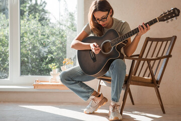 Music and hobbies. A talented young female musician sits alone and composes songs on the guitar....
