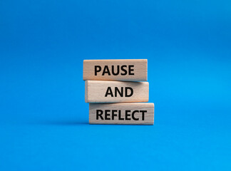 Pause and Reflect symbol. Concept words Pause and Reflect on wooden blocks. Beautiful blue...