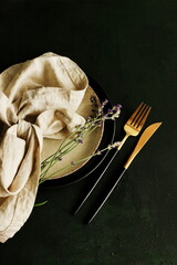 kitchen tableware top view on dark  background Plates,beige linen napkins, cutlery and lavender...