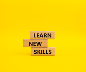 Learn new skills symbol. Concept words Learn new skills on wooden blocks. Beautiful yellow background. Business and Learn new skills concept. Copy space.