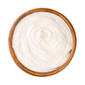 Cream yogurt, in a wooden bowl. Stirred yoghurt, also spelled yogourt or yoghourt, with ten percent fat content. Dairy product, made by bacterial fermentation of mostly cow milk with yogurt cultures.
